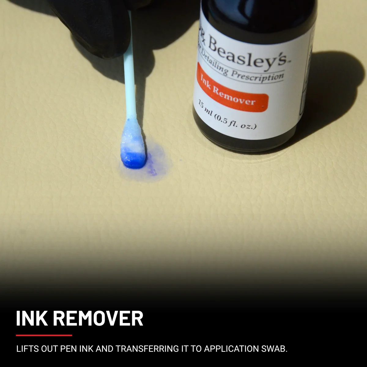 A hand wearing a black glove lifting out an ink stain using a swab dabbed into Ink Remover.